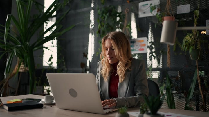 Focused Businesswoman Typing On Laptop In Green Office