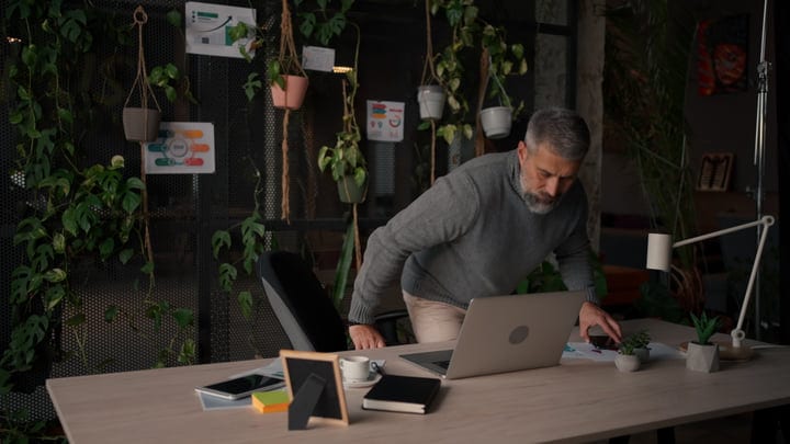 A Businessman Leaning Over Desk In Modern Office Space