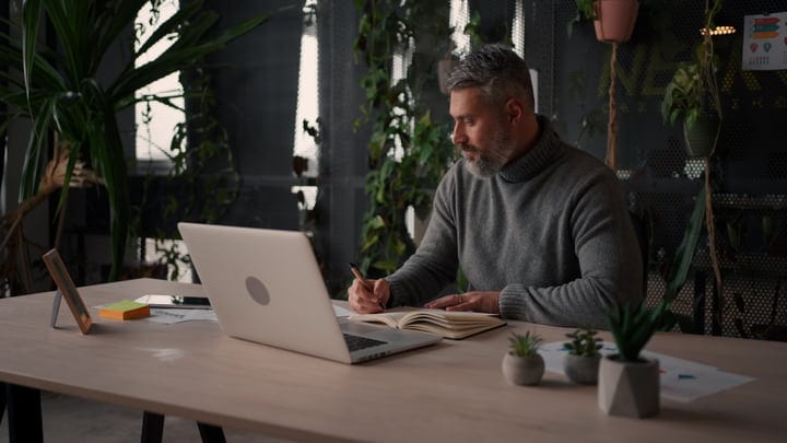 Focused Businessman Writing Notes In Modern Office Space