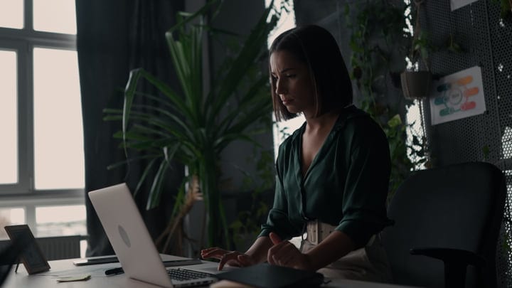 Focused Businesswoman Typing on Laptop in Green Office Space
