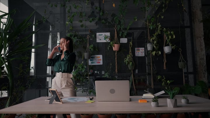 Businesswoman Embraces Greenery During Office Phone Call
