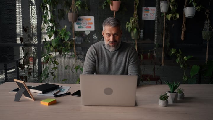 Focused Businessman In Green Office Setting With Laptop
