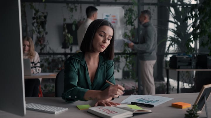 Focused Businesswoman Writing at Her Desk in Modern Office