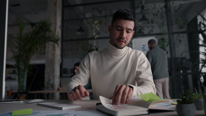 Young Man Working On Notebook At His Desk In A Modern Office