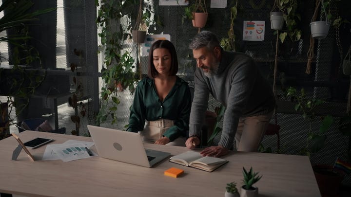 Collaborative Brainstorming Amidst Office Greenery and Laptops