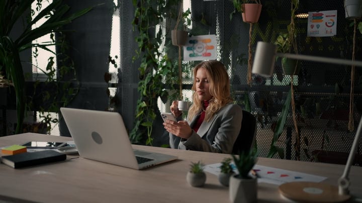 Businesswoman Enjoys Coffee While Checking Her Phone