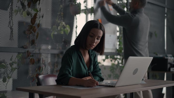 Focused Businesswoman Writing Notes In Modern Office Space