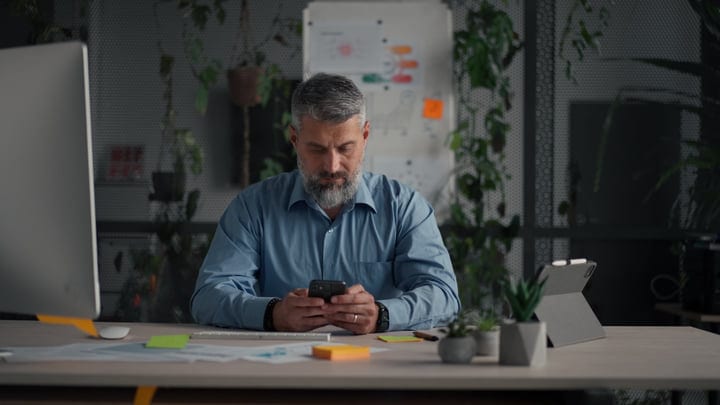 Focused Businessman Engages With Smartphone In Modern Workspace