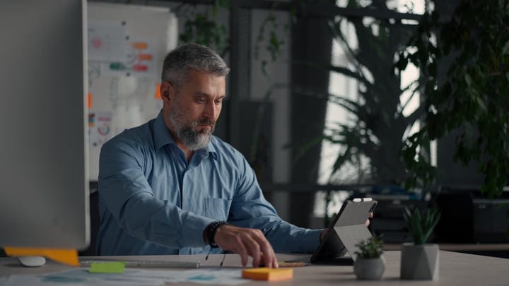 Focused Businessman Engages with Tablet in Modern Office