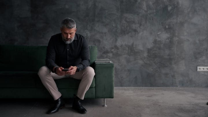 Contemplative Moment: Businessman Seated On Green Sofa