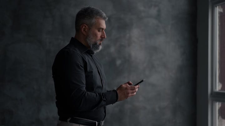 Focused Businessman Engaging with His Smartphone by the Window