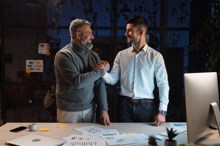 Two Businessmen Celebrate Success With A Handshake At Night
