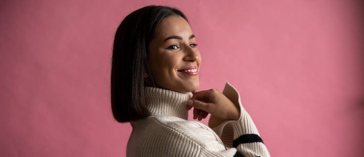 Confident Businesswoman Smiling Against a Pink Backdrop