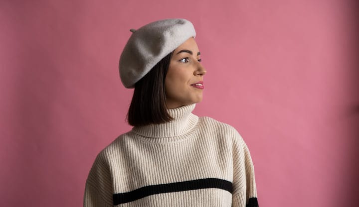 Contemplative Woman in Beret Against Pink Backdrop