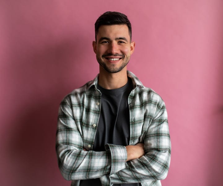 Confident Man With Plaid Shirt And Crossed Arms Smiling In Studio