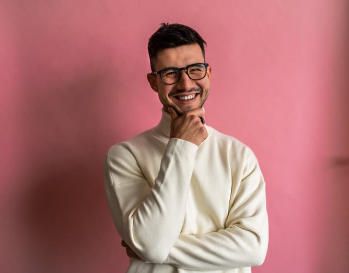Young European Man Smiling Posing With Hand On Chin In Studio