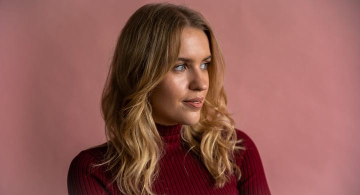 Contemplative Businesswoman Gazes Against a Soft Pink Backdrop