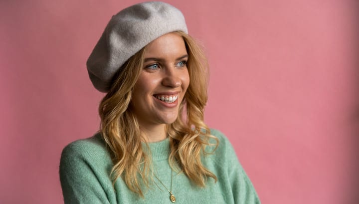 Businesswoman Smiling Against a Pink Background in Office Attire