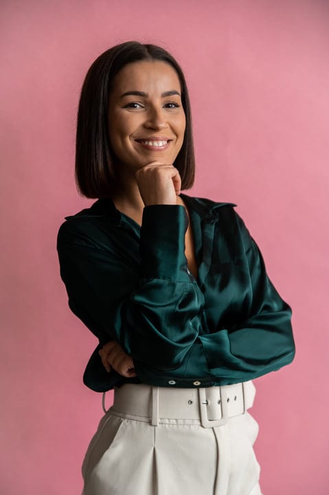 Confident Businesswoman Smiling Against a Bright Pink Backdrop