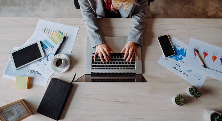 Focused Businesswoman Typing Amidst Documents And Devices