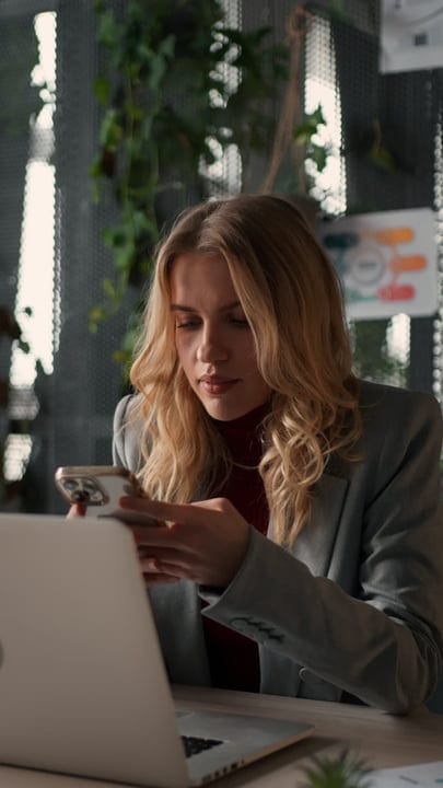 Focused Businesswoman Engages in Smartphone Task at Desk