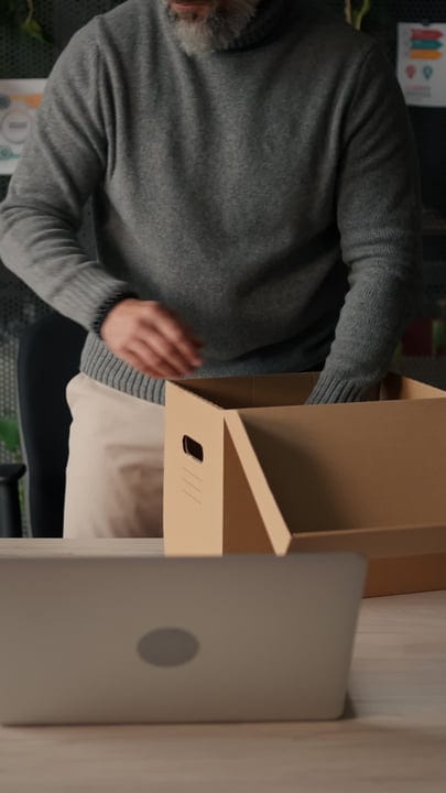 Man Organizing Office Supplies Into A Cardboard Box