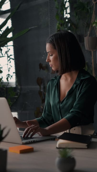Focused Businesswoman Typing in Modern Green Office Space