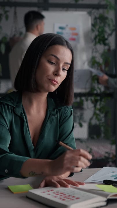 Focused Businesswoman Sketching Ideas In Modern Workspace