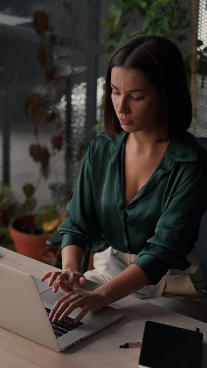 Focused Businesswoman Typing in a Green Office Setting