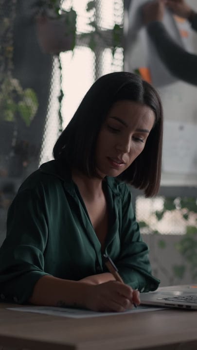 Focused Businesswoman Writing In A Green Office Space