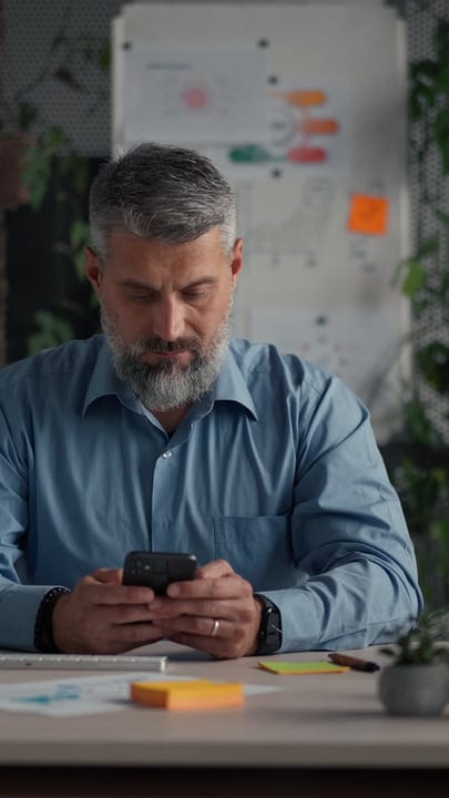 Focused Professional Engages with Smartphone at Desk