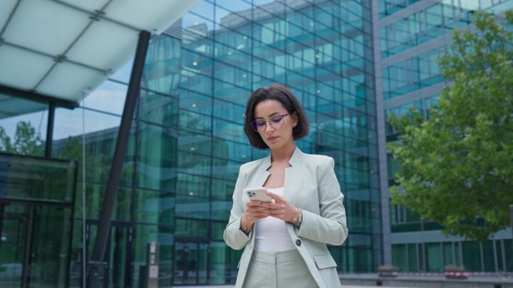 Focused Businesswoman Texting Outside a Modern Office in Vienna
