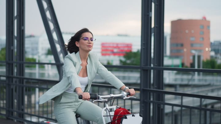 Confident Businesswoman Pedals Across Modern Vienna Bridge