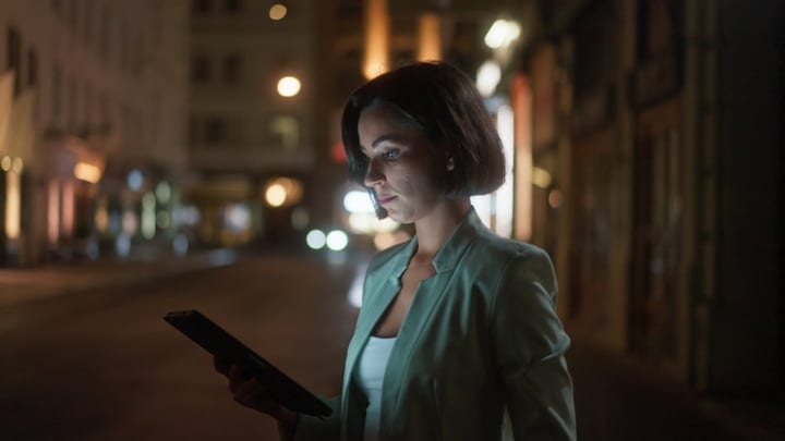 Focused Businesswoman Engages with Tablet Under Vienna's Night Lights