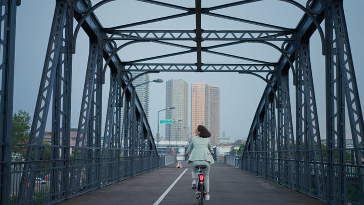 Businesswoman Cycling Across Vienna Bridge In Morning Light