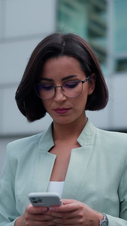 Focused Businesswoman Engages With Her Smartphone Outdoors