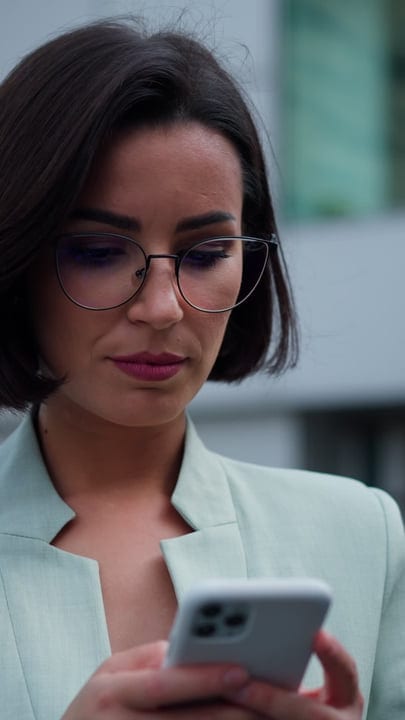 Focused Businesswoman Engages With Her Smartphone Outdoors
