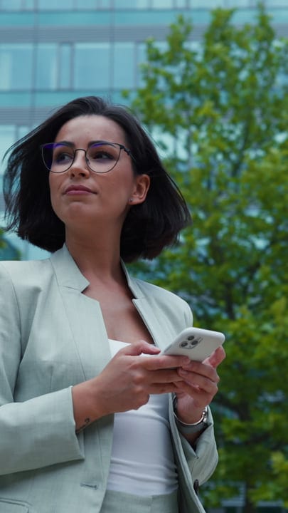 Confident Businesswoman Engages With Her Smartphone Outdoors