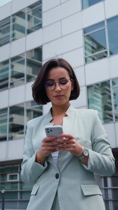 Confident Businesswoman Engages With Her Smartphone Outdoors