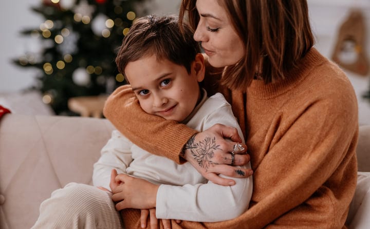 Mother Embraces Her Son Amidst Christmas Lights