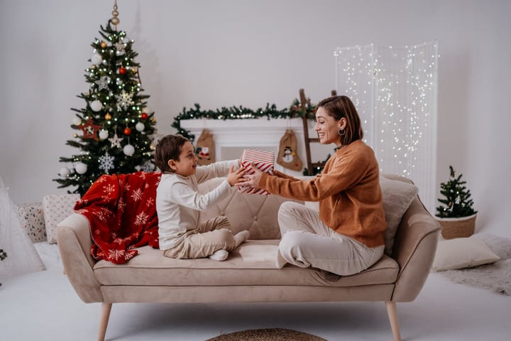 Joyful Gift Exchange Between Mother And Child On Sofa