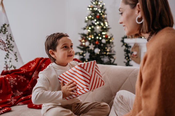 Young Child Shares Joyful Moment With Mother At Christmas