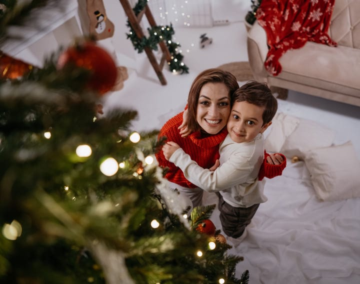 Mother And Child Embrace By The Christmas Tree
