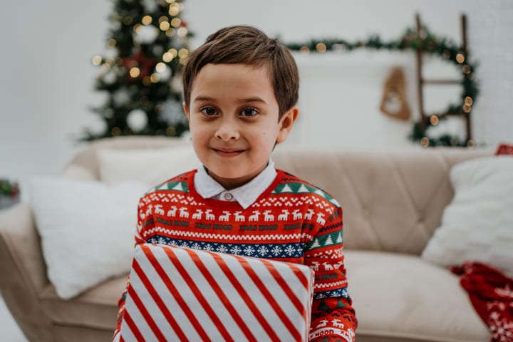 Joyful Child Embraces Christmas Gift In Festive Living Room