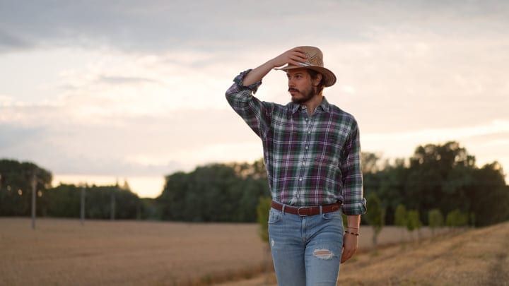 Contemplative Farmer Stands Amidst Golden Fields at Dusk