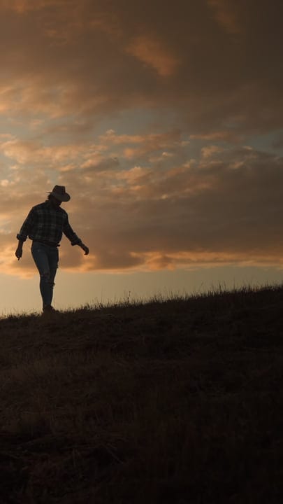 A Farmer Walks Into The Sunset With Purpose