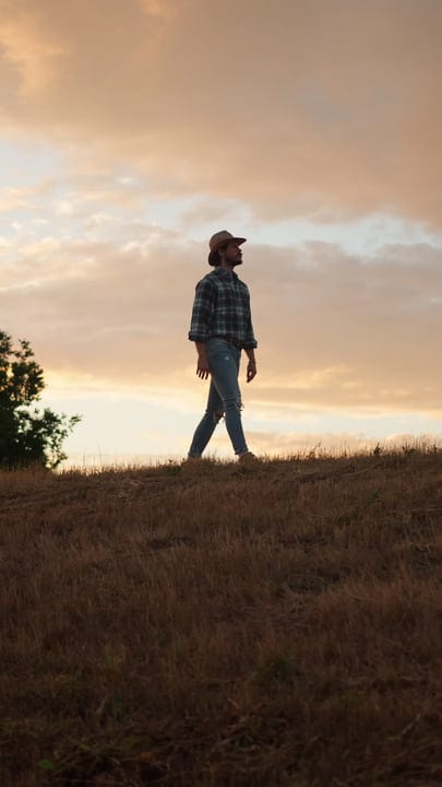 A Farmer Embraces Sunset Stroll On Open Field
