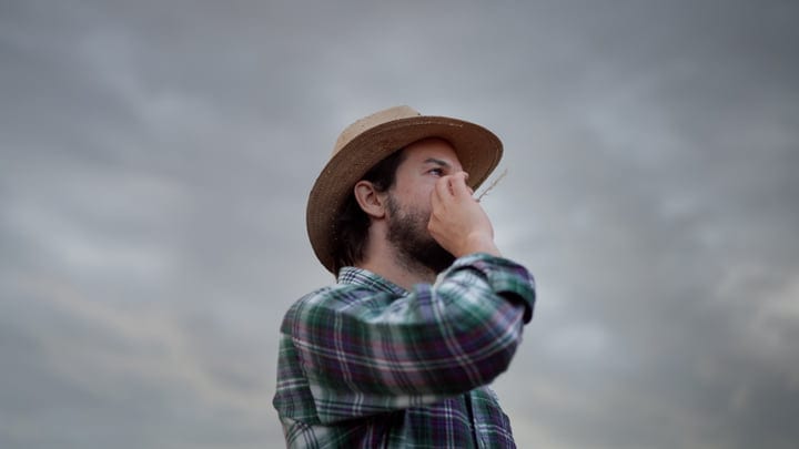Contemplative Farmer Gazes At Overcast Sky