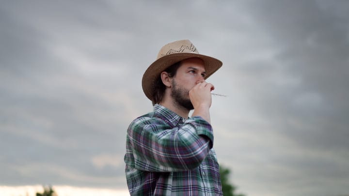 Pensive Farmer Gazes Outward Under A Cloudy Sky