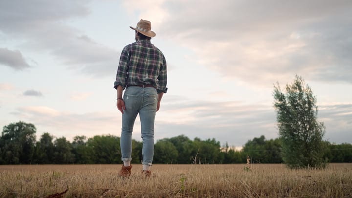A Farmer Embraces The Sunrise In A Golden Field